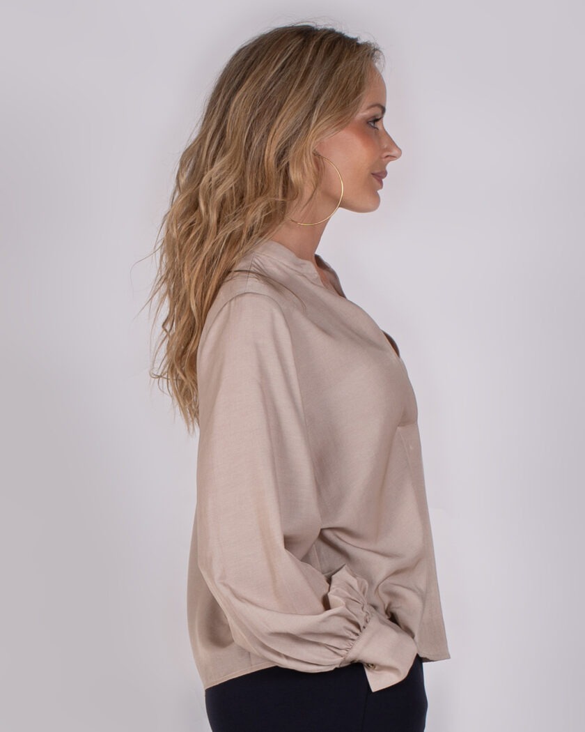 Vrouw in profiel met lang golvend haar, gekleed in een beige blouse uit de Studio AW25-26 collectie.