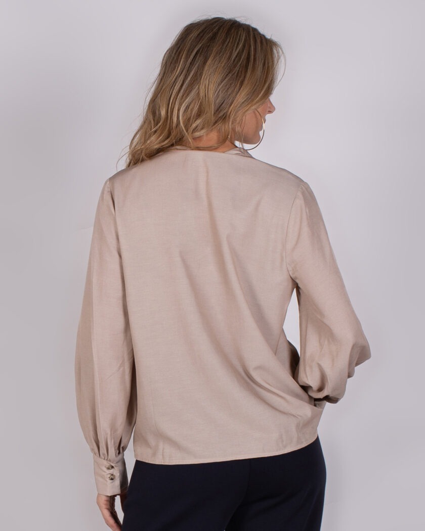Vrouw van achteren in beige blouse met lange mouwen uit de Studio AW25-26 collectie.