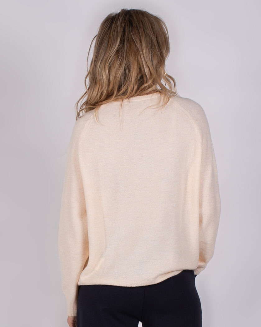 Achteraanzicht van een vrouw die een lichtbeige trui uit de Studio AW25-26 collectie draagt.