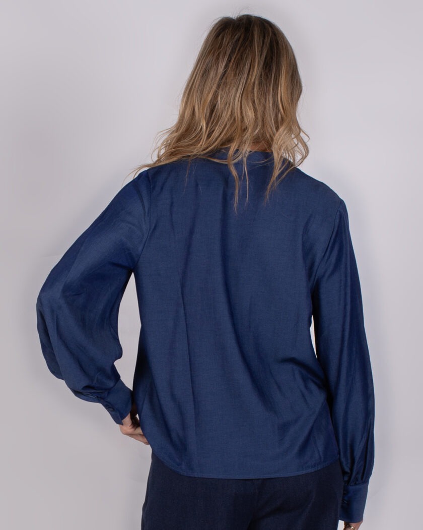 Achteraanzicht van een vrouw die een donkerblauwe blouse draagt uit de Studio AW25-26 collectie.
