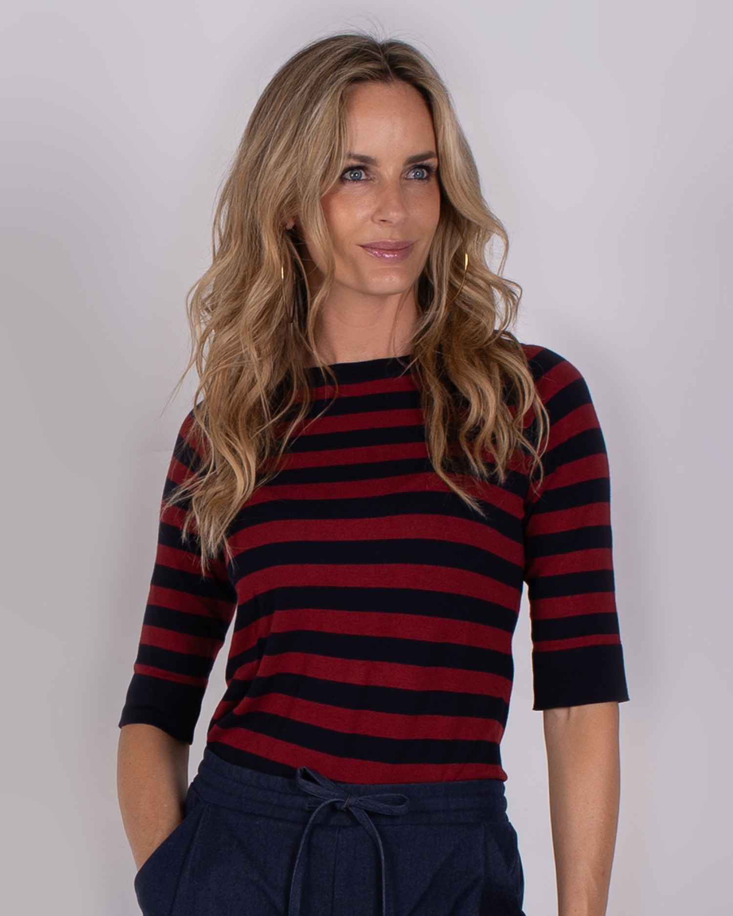 Vrouw draagt een rood-zwart gestreepte top met halve mouwen uit de Studio AW25-26 collectie.