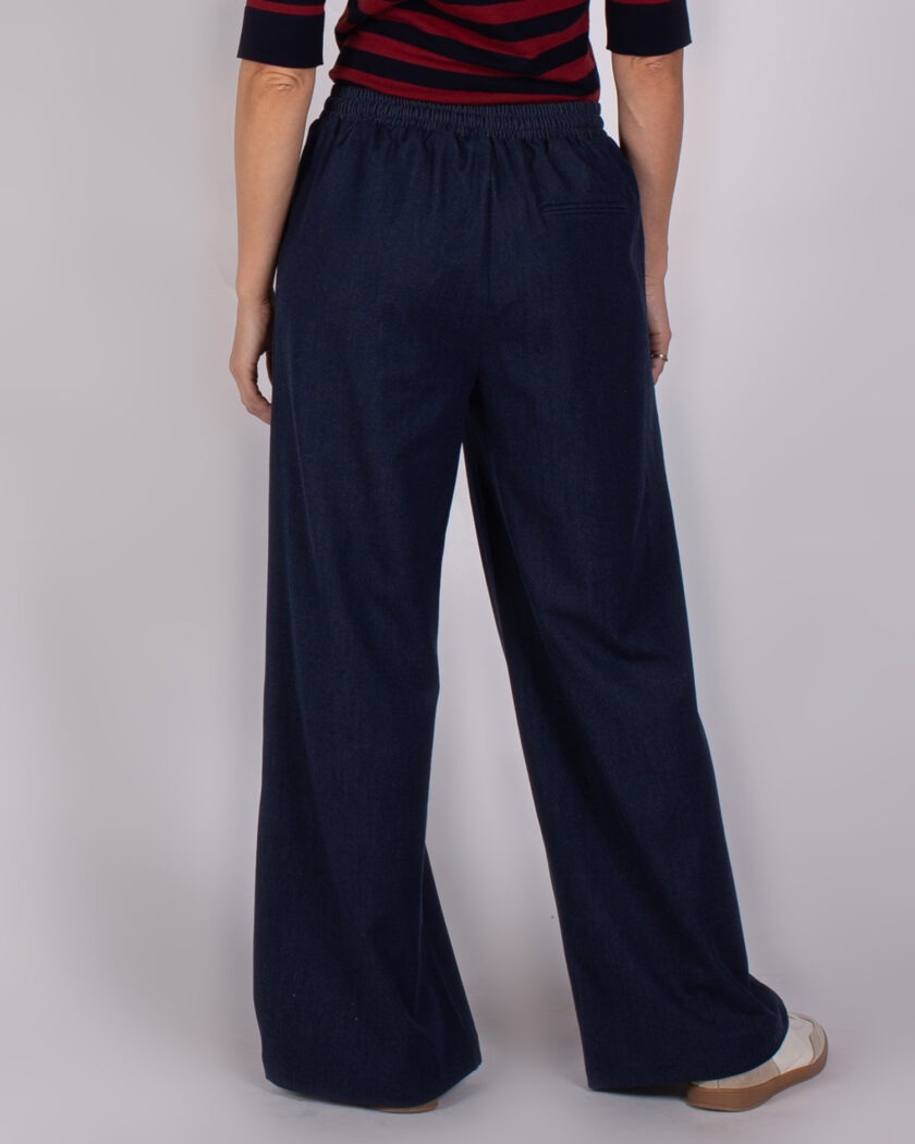 Achteraanzicht van een persoon die een donkerblauwe, wijde Studio AW25-26-147 broek draagt.