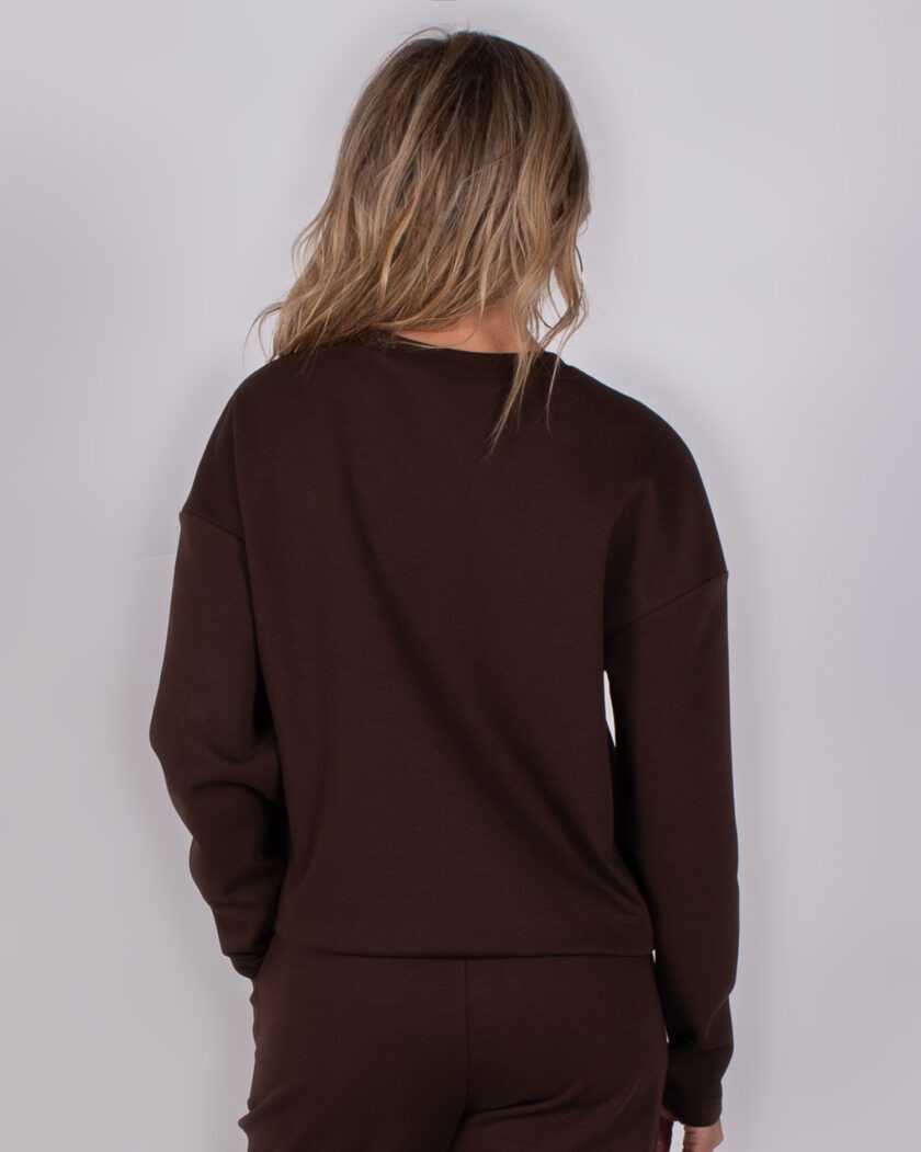 Achteraanzicht van een vrouw in een donkerbruine lounge set uit de Studio AW25-26 collectie.