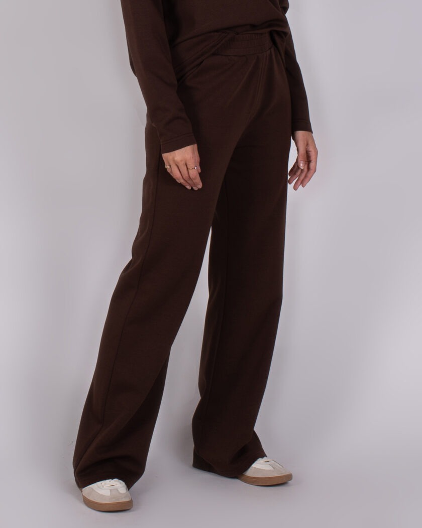 Model draagt een bruine, wijde broek van Studio AW25-26-175 met een bijpassende top en witte sneakers.