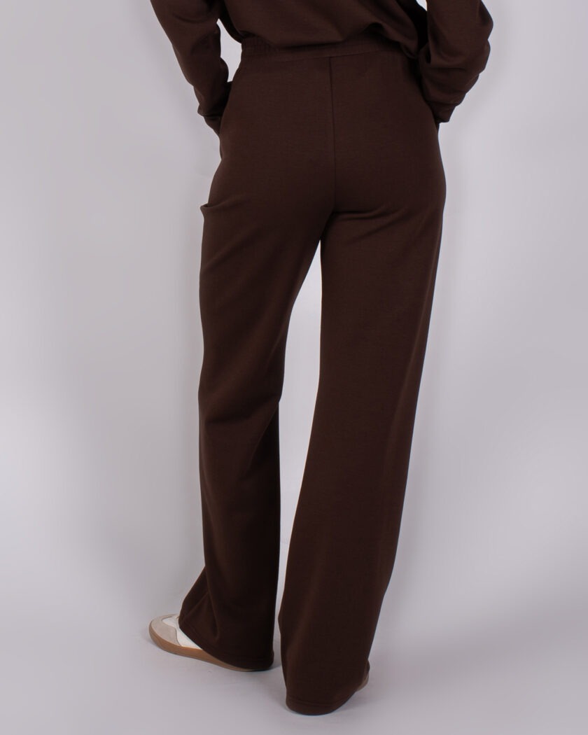 Achteraanzicht van een persoon die een donkerbruine Studio AW25-26-176 broek draagt met wijde pijpen.