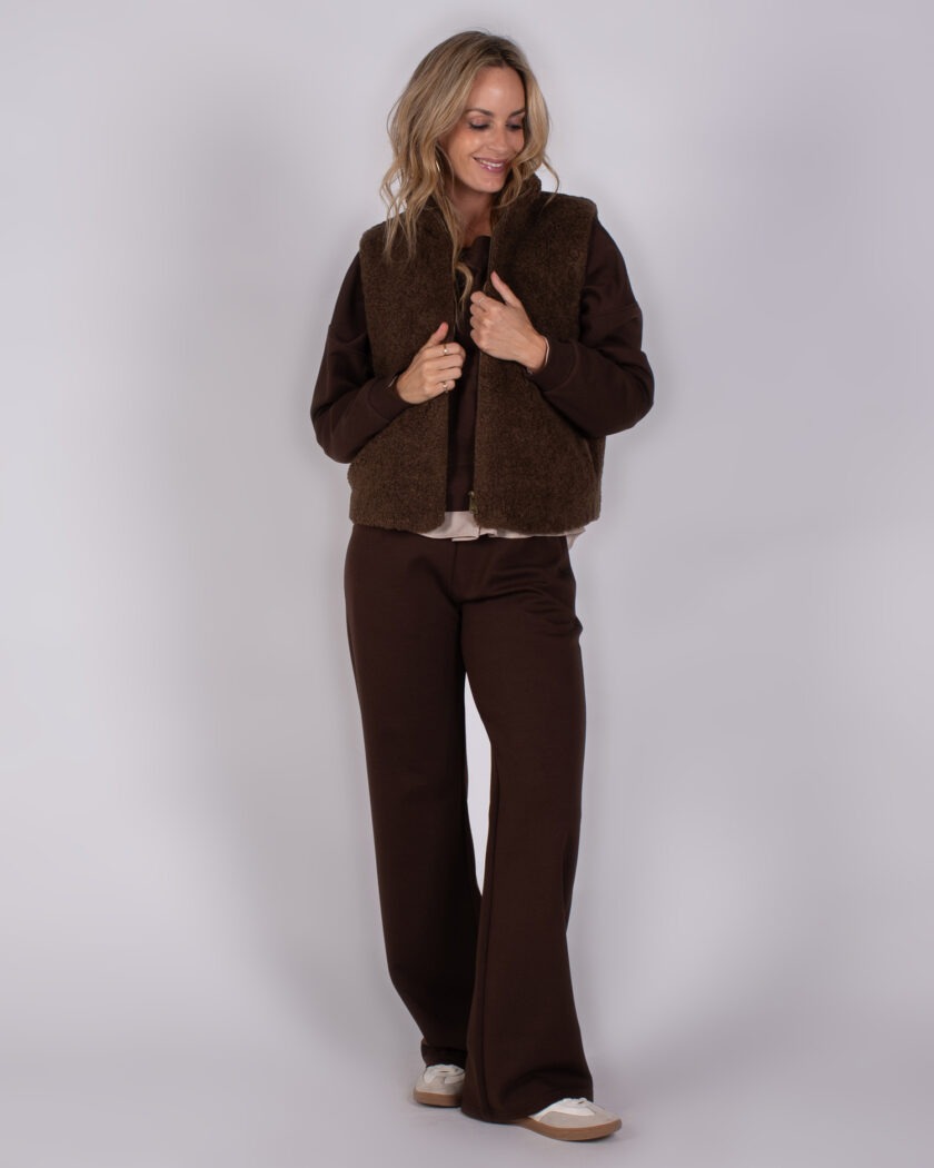 Vrouw draagt een donkerbruine Lounge-set met een bijpassend teddy bodywarmer uit de Studio AW25-26 collectie.