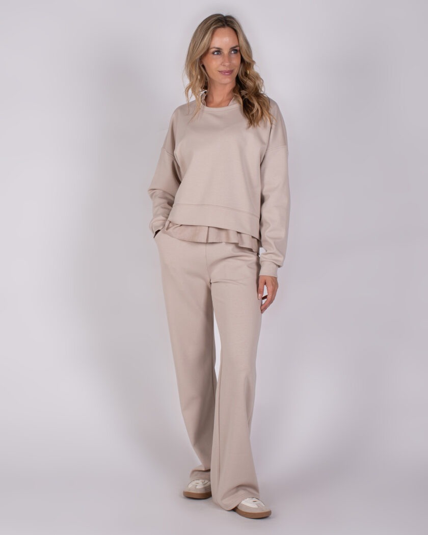 Vrouw draagt een beige loungepak uit de Studio AW25-26 collectie.