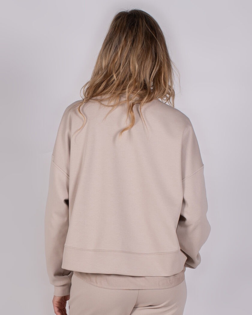 Achteraanzicht van een model dat een beige Studio AW25-26-192 sweatshirt en bijpassende broek draagt.