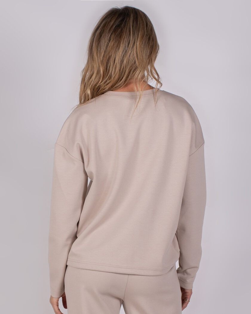 Achteraanzicht van een model dat een beige Studio AW25-26-201 loungewear-set draagt.