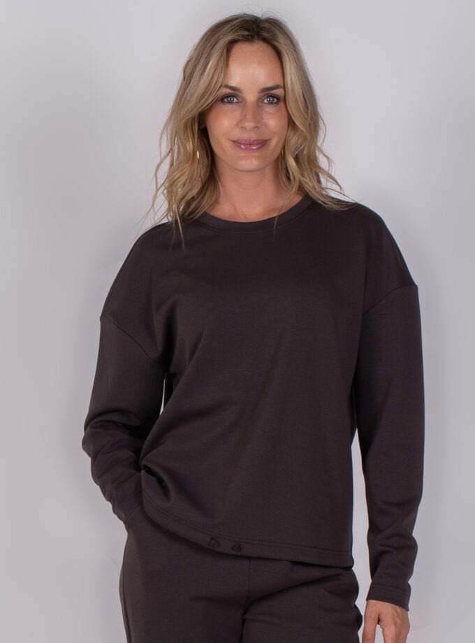 Vrouw draagt een donkerbruine longsleeve top en bijpassende broek uit de Studio AW25-26-210 collectie.