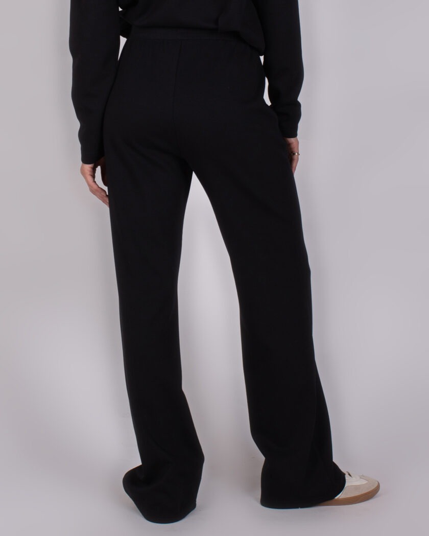 Achteraanzicht van een persoon gekleed in een zwarte broek uit de Studio AW25-26-231 collectie.