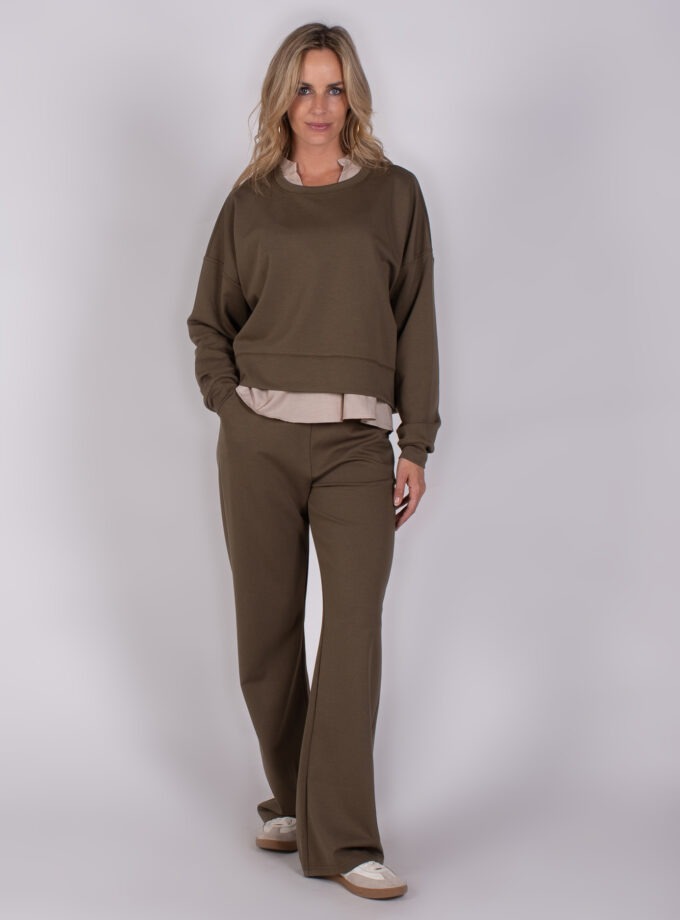 Vrouw draagt een comfortabele olijfgroene lounge-set met wijde broek en sweatshirt uit de Studio AW25-26-232 collectie.