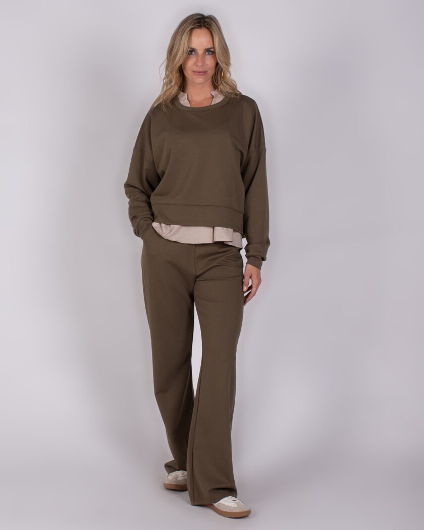 Vrouw draagt een comfortabele olijfgroene lounge-set met wijde broek en sweatshirt uit de Studio AW25-26-232 collectie.
