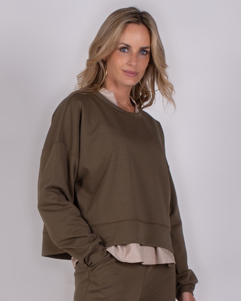Vrouw draagt een comfortabele, olijfgroene lounge set uit de Studio AW25-26 collectie.