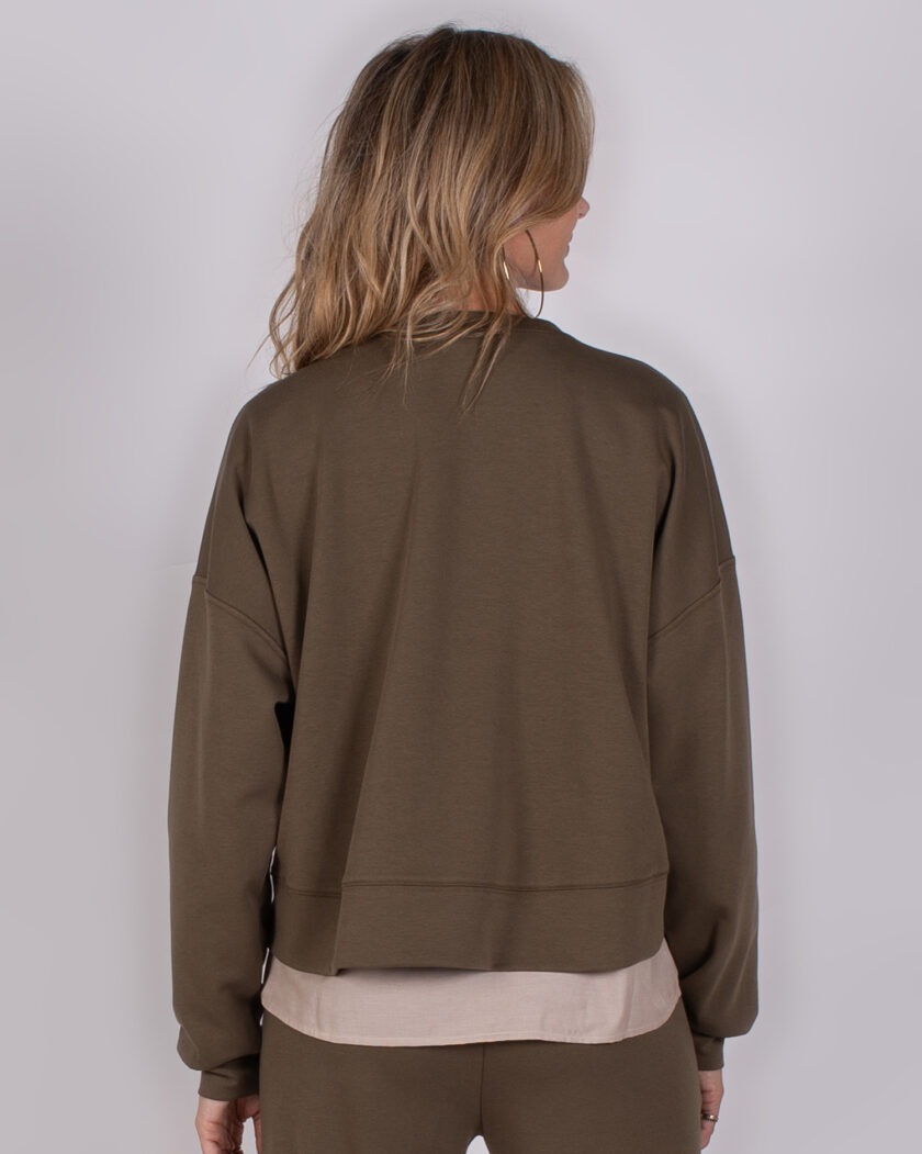 Vrouw van achteren in een olijfgroene Studio AW25-26-236 sweater met bijpassende broek.
