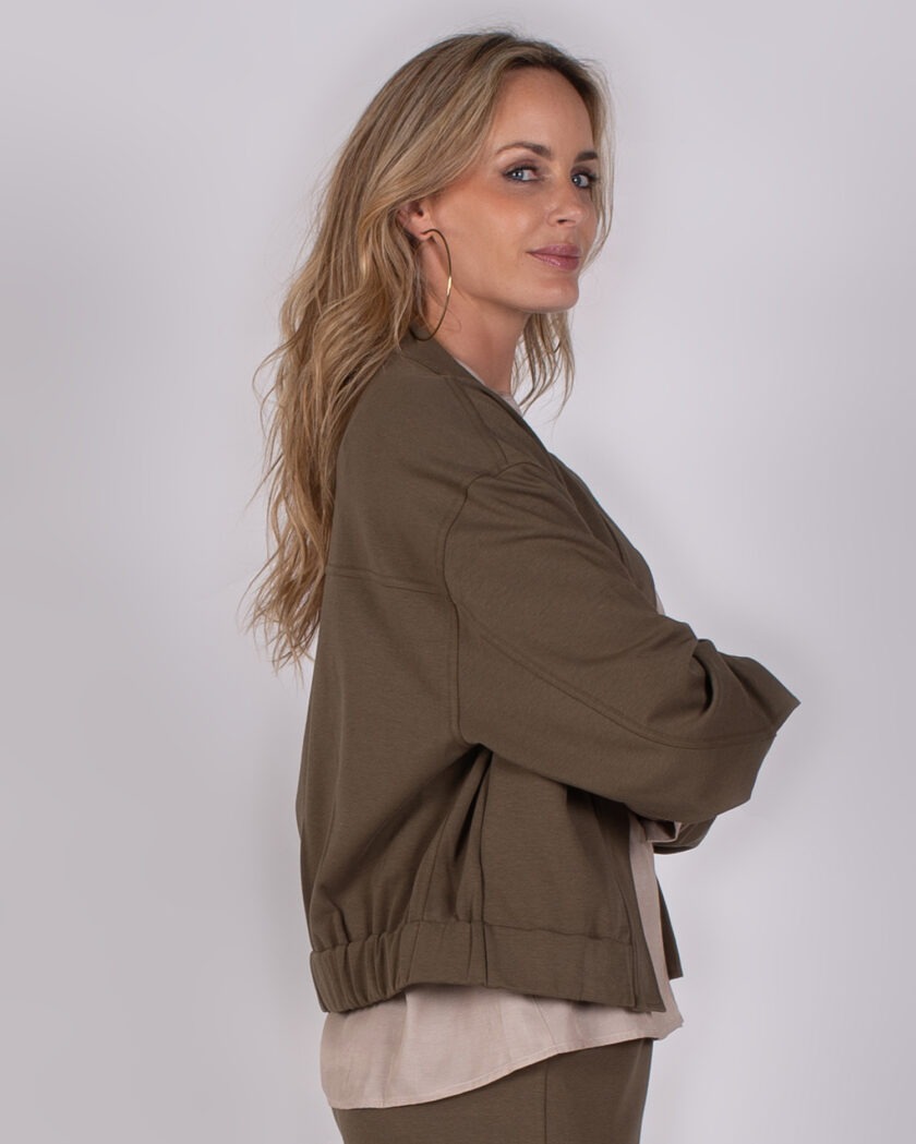 Vrouw in zijaanzicht draagt een olijfgroene Studio AW25-26-241 jas met beige top eronder.