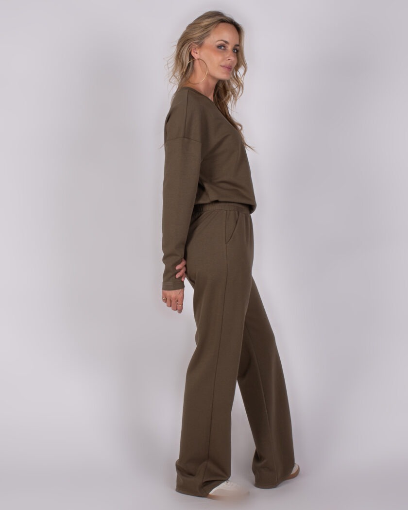 Vrouw in een olijfgroen loungewearpak met wijde broek en lange mouwen uit de Studio AW25-26-247 collectie.