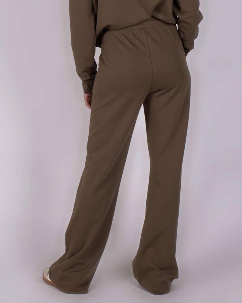 Achteraanzicht van een model in een losse, bruine Studio_AW25-26-248 broek met rechte pijpen.