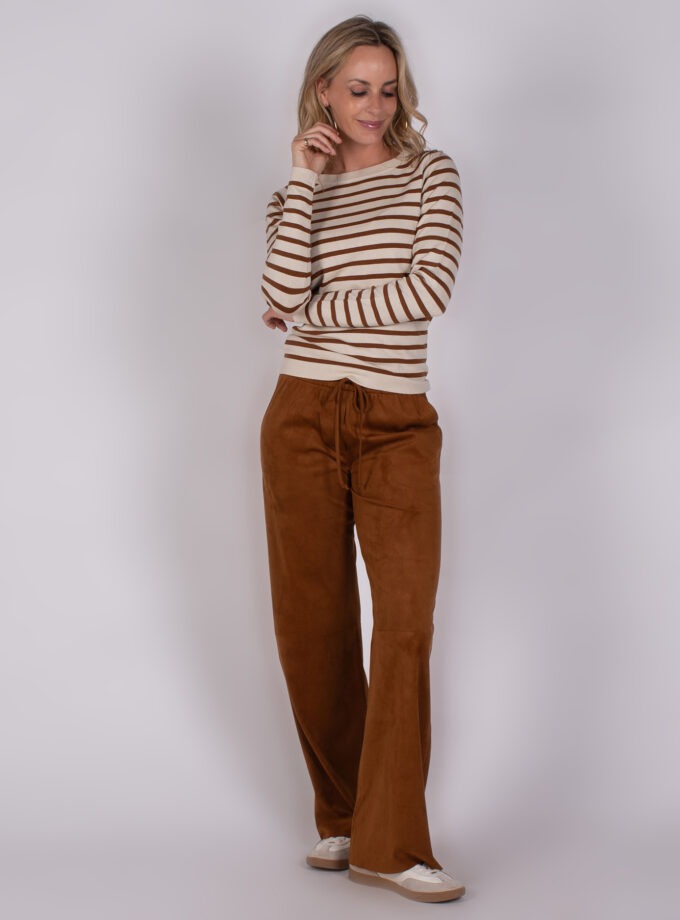 Vrouw met gestreepte trui en losse, bruine broek uit Studio AW25-26-250 collectie.