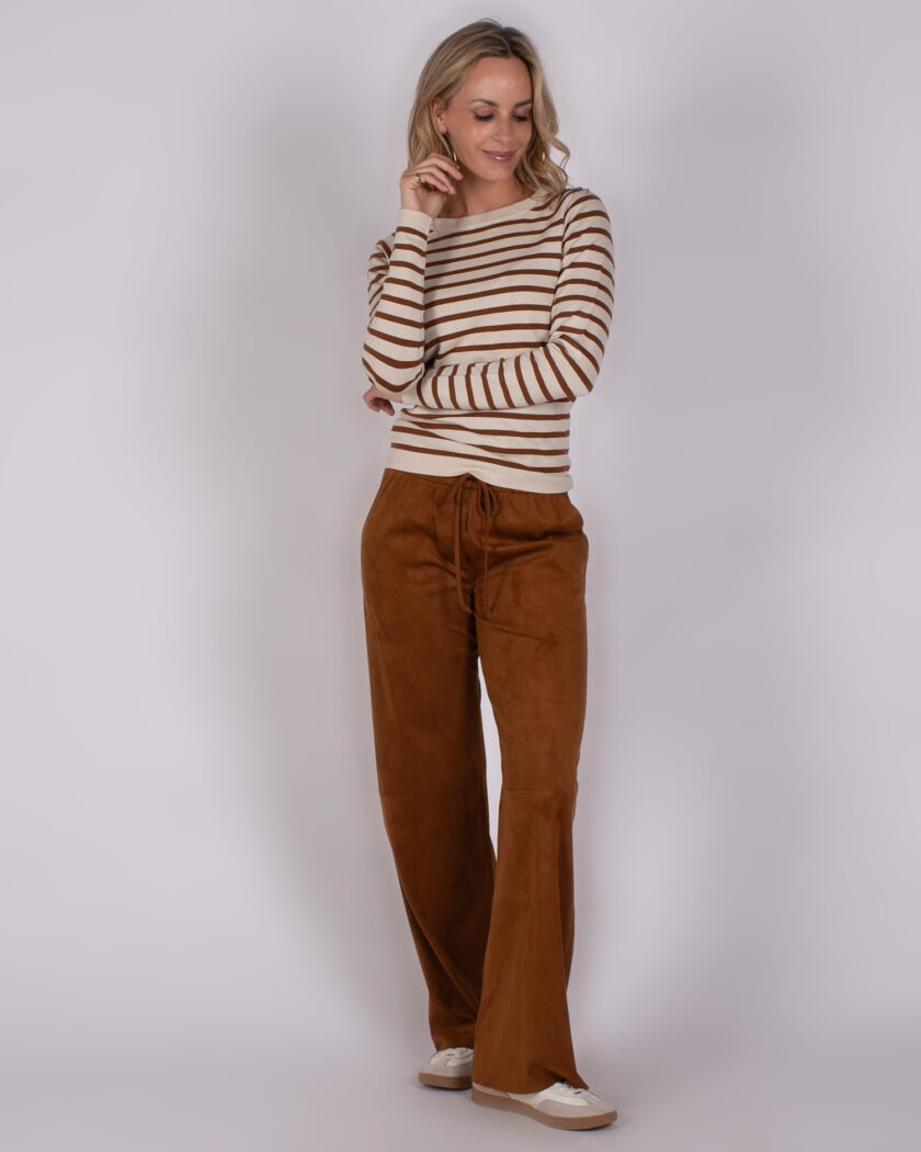 Vrouw met gestreepte trui en losse, bruine broek uit Studio AW25-26-250 collectie.