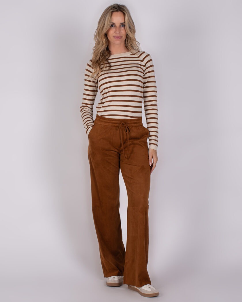 Vrouw draagt een beige trui met bruine strepen en wijde, bruine broek van Studio AW25-26-253.