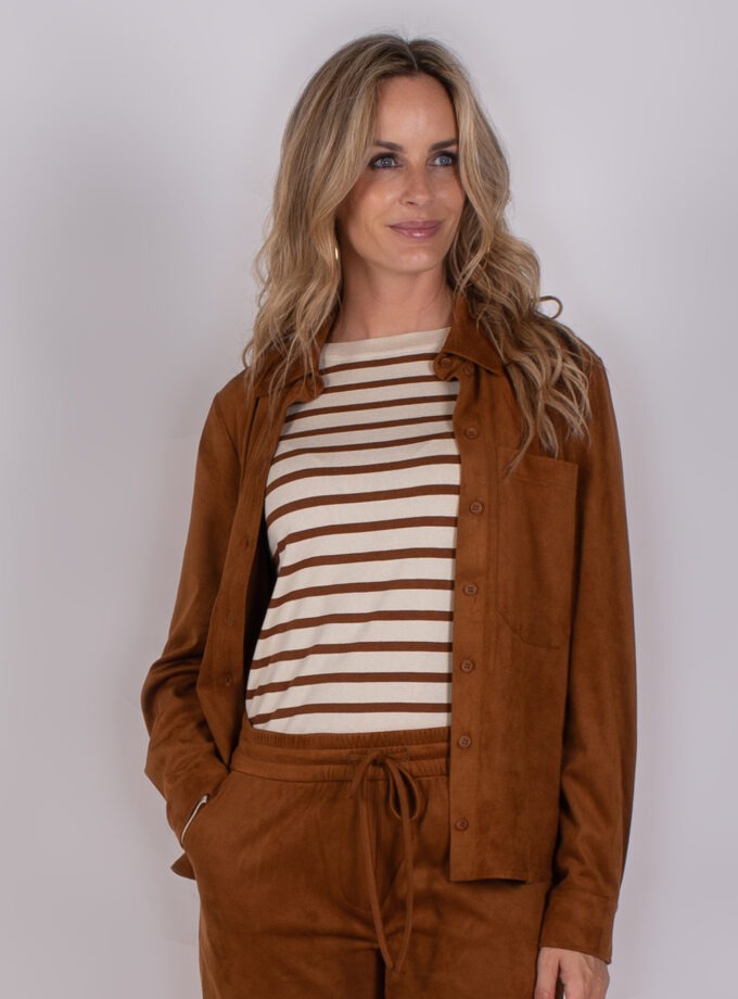 Vrouw draagt een bruin Studio AW25-26-258 pak met een beige en bruin gestreepte top.