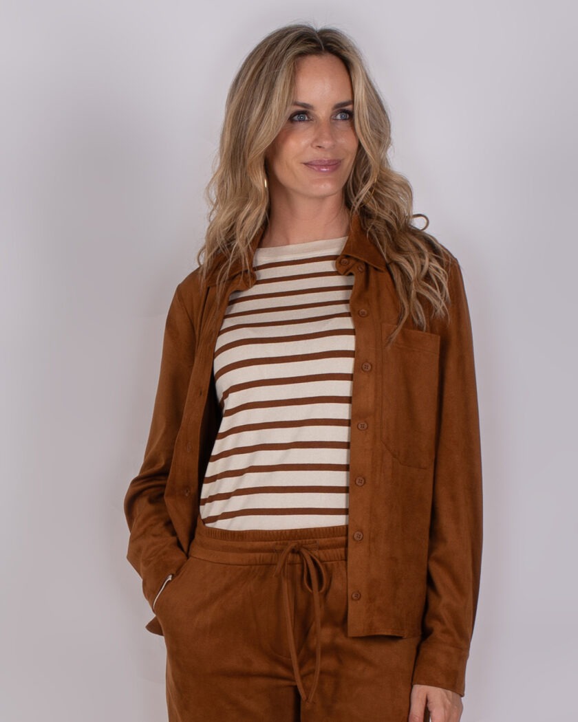 Vrouw draagt een bruin Studio AW25-26-258 pak met een beige en bruin gestreepte top.