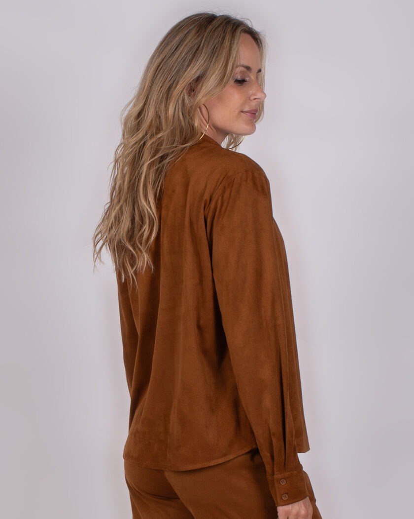 Vrouw met lang blond haar draagt een bruin suède-achtige blouse en bijpassende broek uit de Studio AW25-26 collectie.