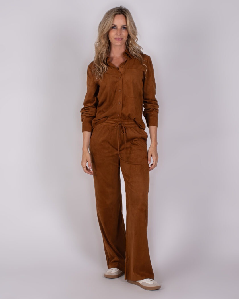 Vrouw draagt een bruin suèdelook Studio_AW25-26-264 pak met overhemd en wijde broek.
