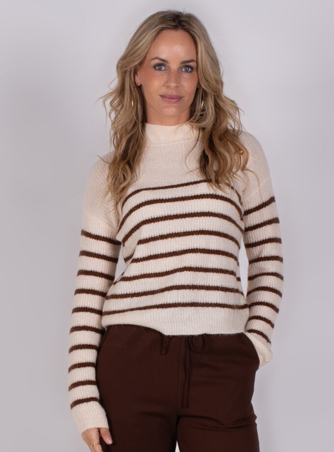 Vrouw draagt een crèmekleurige trui met bruine strepen en een bruine broek uit de Studio AW25-26-29 collectie.