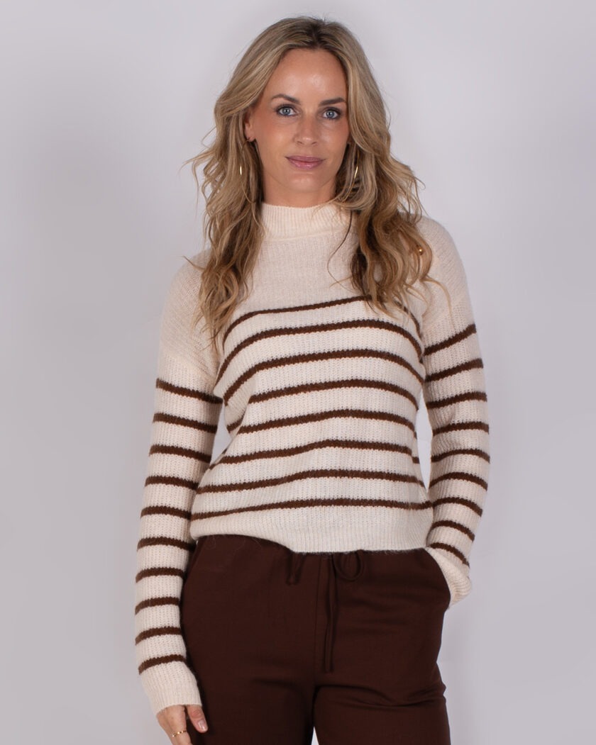 Vrouw draagt een crèmekleurige trui met bruine strepen en een bruine broek uit de Studio AW25-26-29 collectie.