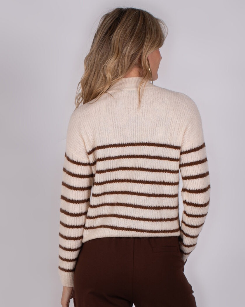 Vrouw van achteren gezien die een crèmekleurige trui met bruine strepen uit de Studio AW25-26-31 collectie draagt.