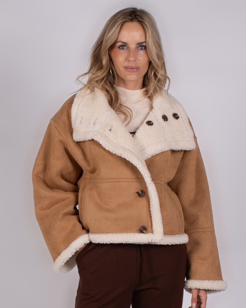 Vrouw draagt een camel-kleurige shearling jas met grote kraag uit de Studio AW25-26 collectie.