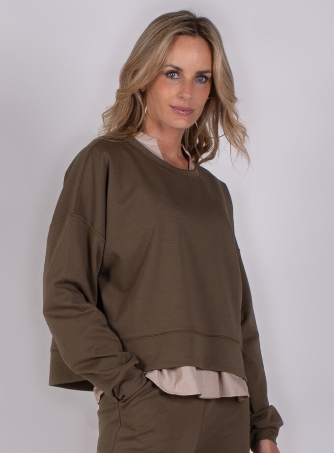 Vrouw draagt een comfortabele, olijfgroene loungewear-set met een beige top eronder uit de Studio AW25-26 collectie.