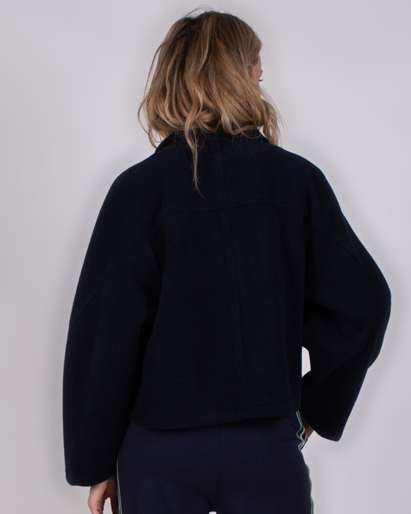 Achteraanzicht van een vrouw die een donkerblauwe Studio AW25-26-59 jas draagt.