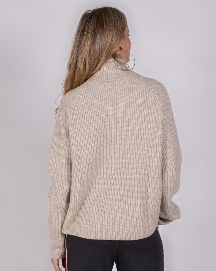 Vrouw van achteren in een beige, geribde Studio AW25-26-65 trui met opstaande kraag.