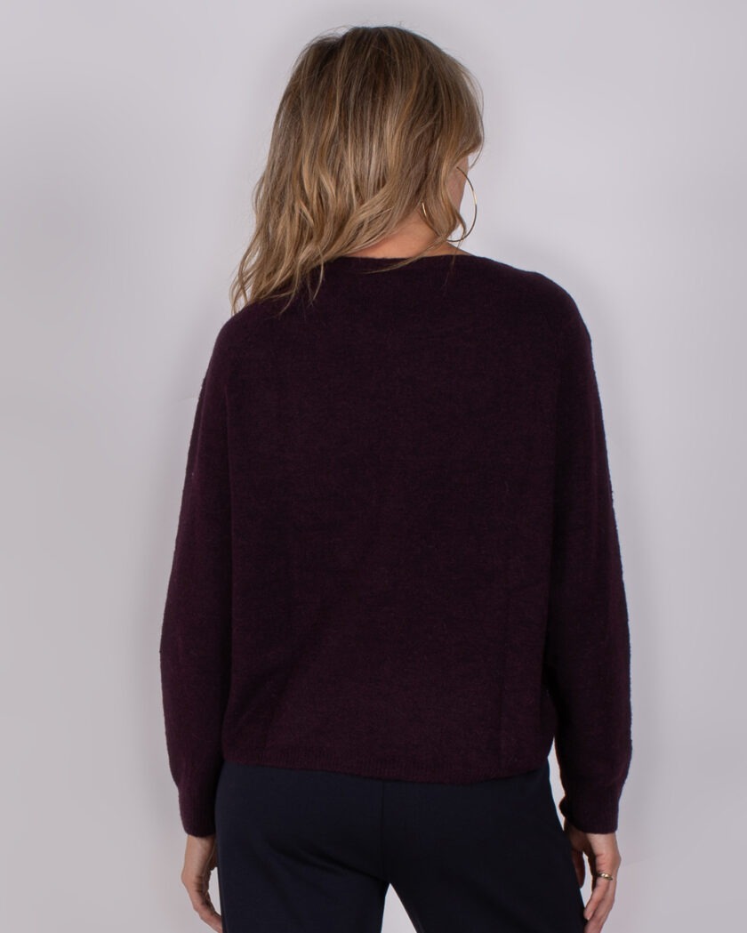 Achteraanzicht van een vrouw die een donkerpaarse trui uit de Studio AW25-26 collectie draagt.
