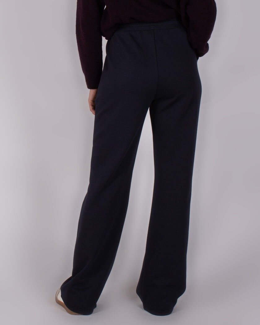 Achteraanzicht van een model dat een donkerblauwe, rechte Studio AW25-26-97 broek draagt.
