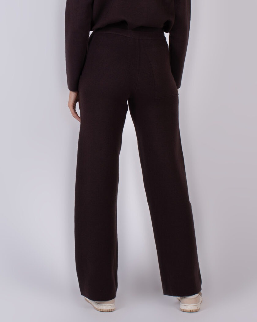 Achteraanzicht van een persoon gekleed in een donkerbruine broek en trui uit de Studio AW25-26 collectie.