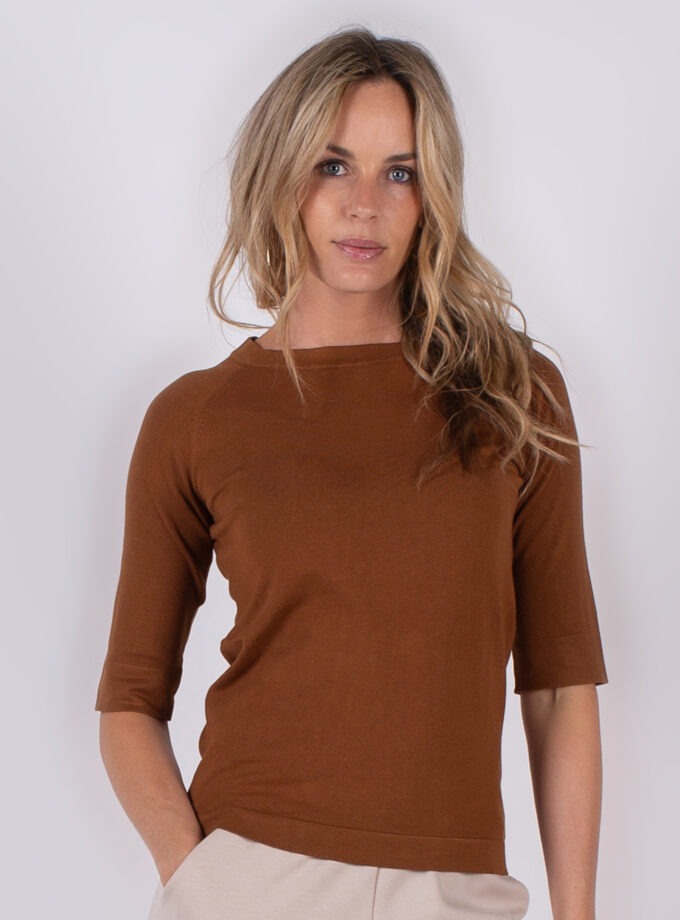Vrouw draagt een bruin shirt met halflange mouwen uit de Studio AW25-26 collectie.