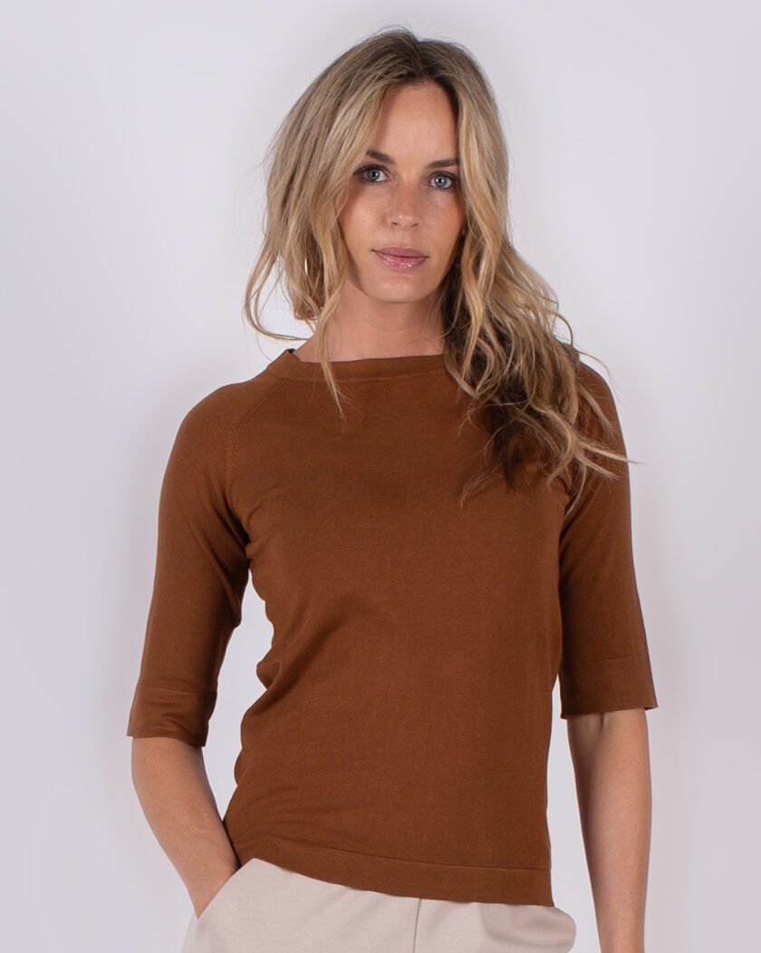 Vrouw draagt een bruin shirt met halflange mouwen uit de Studio AW25-26 collectie.