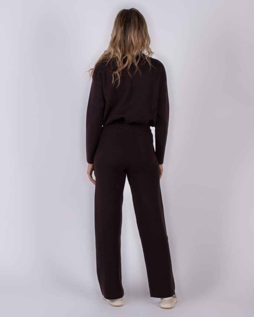 Vrouw van achteren in een donkerbruin loungepak met lange mouwen en wijde broek, uit de Studio AW25-26 collectie.