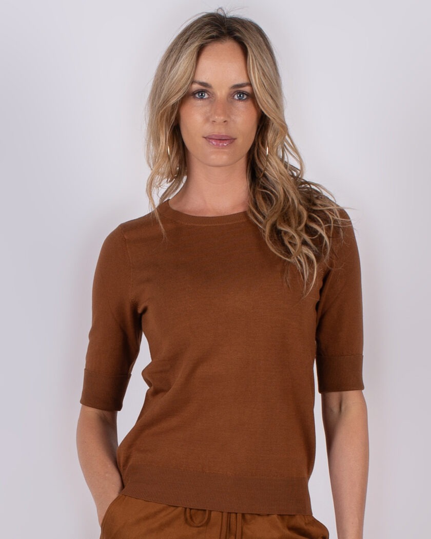 Vrouw poseert in een bruin, half-mouw gebreid shirt uit de Studio AW25-26 collectie.