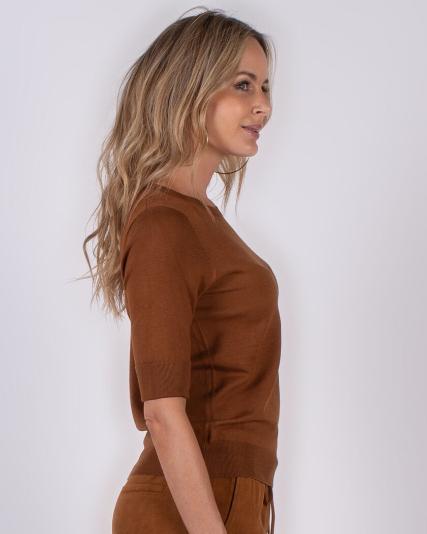 Vrouw in profiel gekleed in een bruin, half mouw truitje en bijpassende broek uit de Studio AW25-26 collectie.