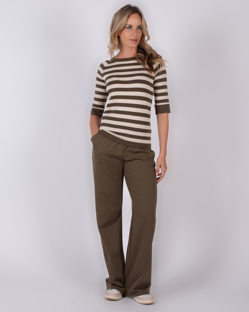 Vrouw met los haar draagt een bruin-wit gestreepte top en wijde, bruine broek uit de Studio AW25-26 collectie.