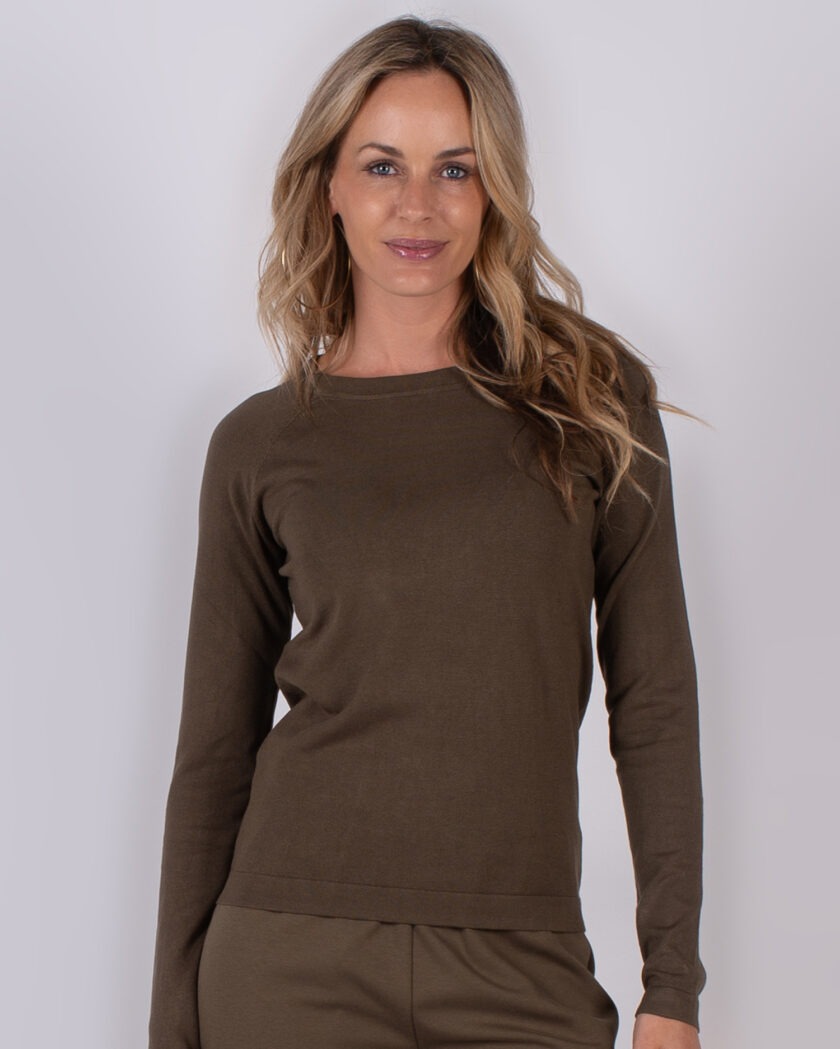 Vrouw poseert in een bruine, lange mouwen top en bijpassende broek uit de Studio AW25-26 collectie.