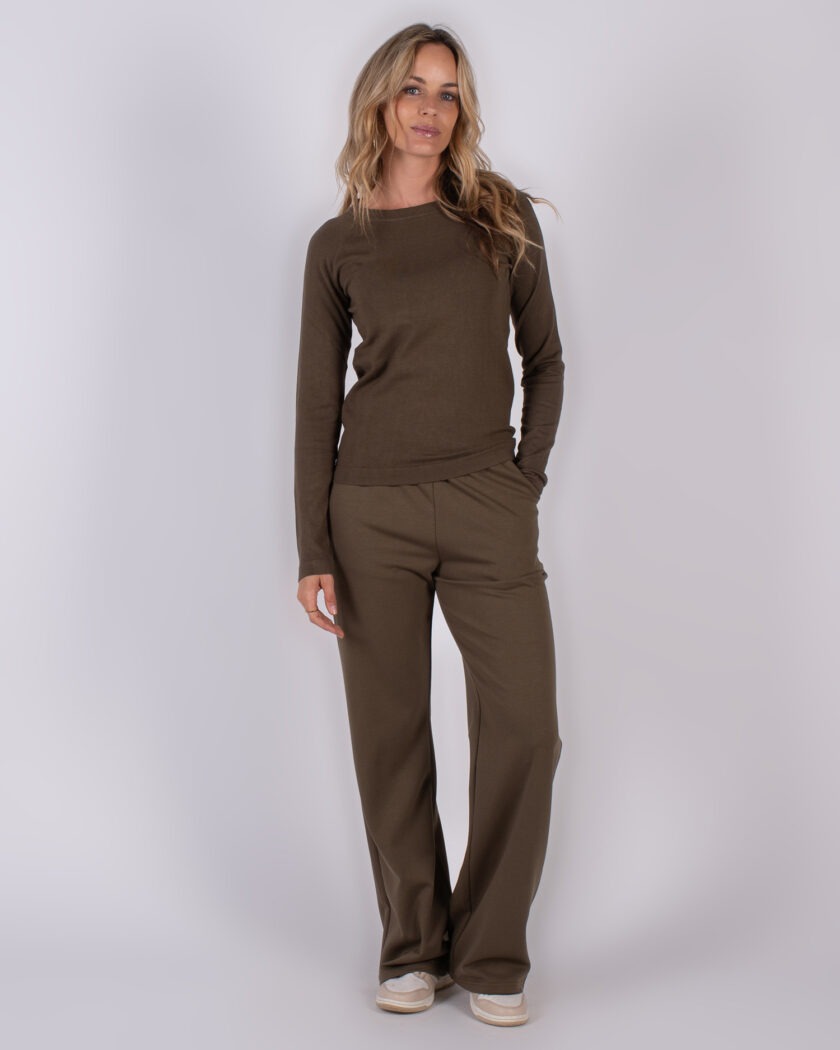 Vrouw draagt een olijfgroene lounge-set met lange mouwen en wijde broek, uit de Studio AW25-26 collectie.