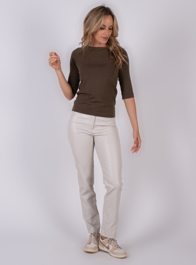 Vrouw draagt een bruine top met driekwartmouwen en lichtbeige broek uit de Studio AW25-26 collectie.