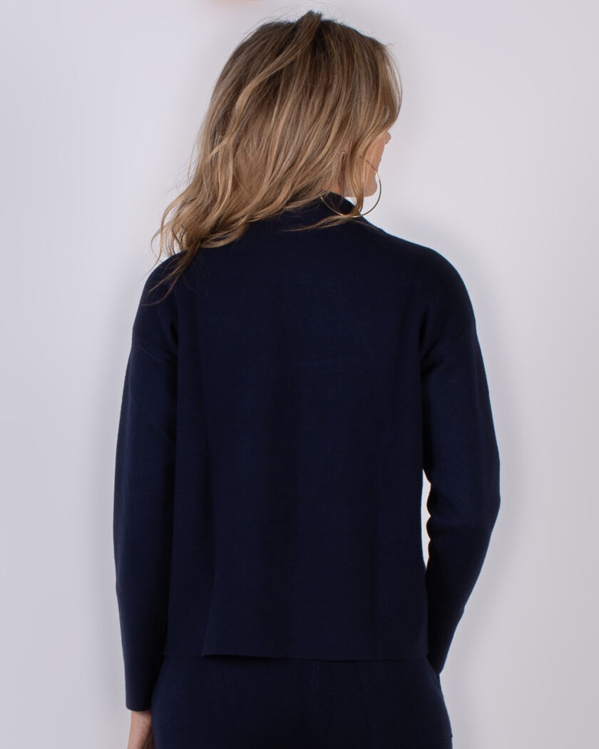 Vrouw van achteren in een donkerblauwe trui uit de Studio AW25-26 collectie.
