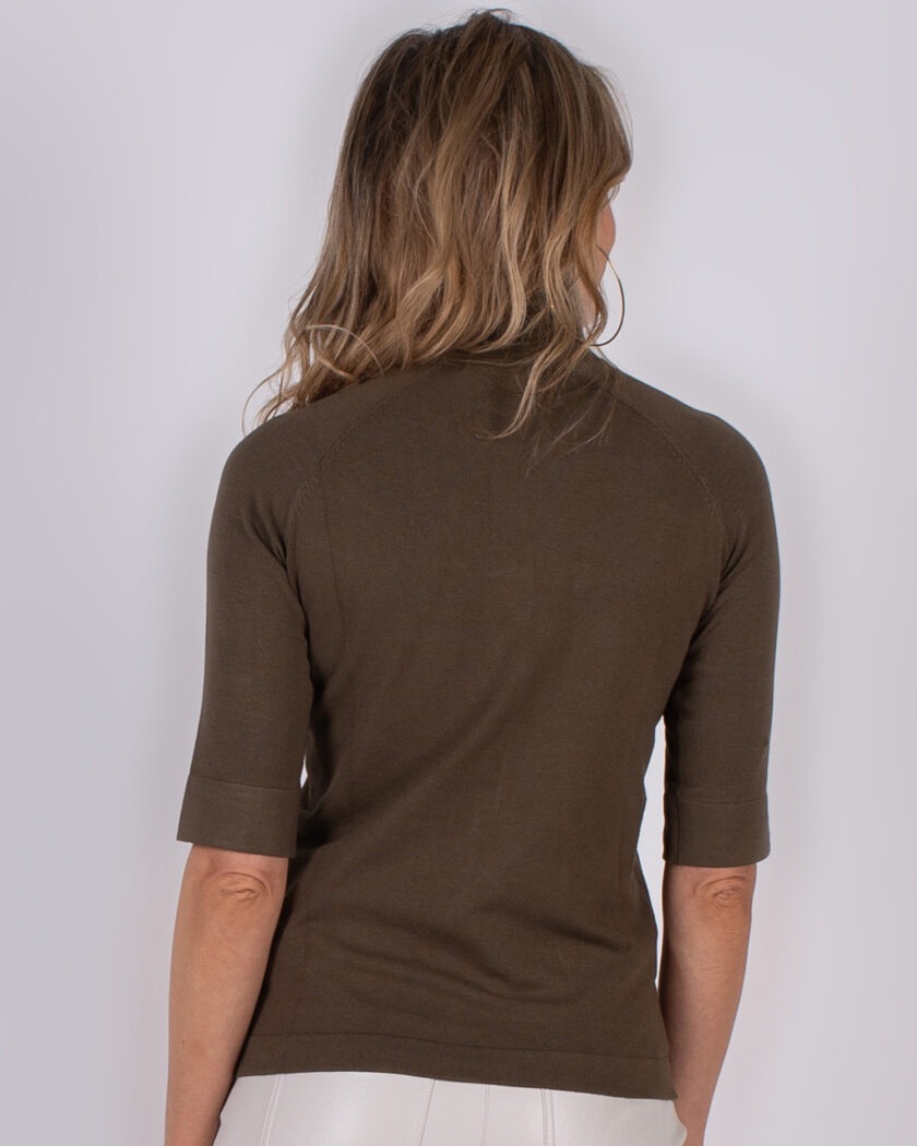 Vrouw van achteren in een bruin Studio AW25-26 top met halve mouwen en witte broek.